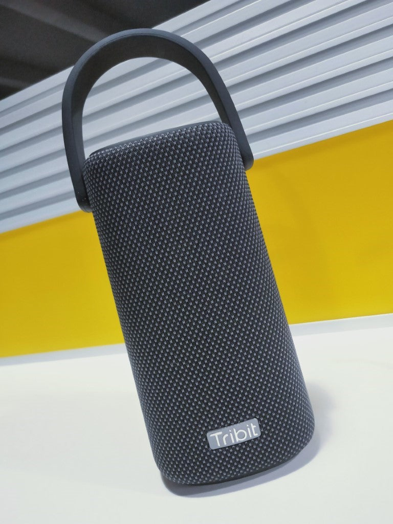 The Tribit StormBox Pro, cylindrical in shape with a fabric mesh covering. A sturdy handle is attached at the top.