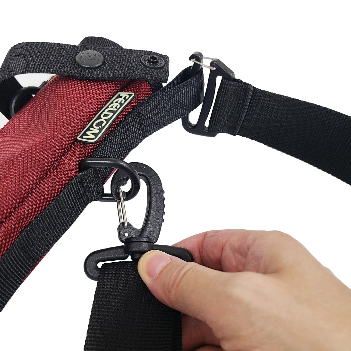 Close-up of a person adjusting a black strap clip on the top of a burgundy and black cane pouch.