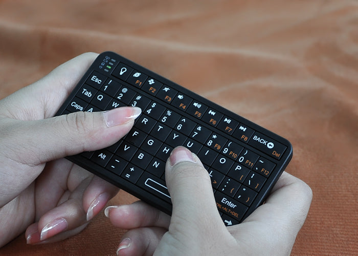 A person holding a black Rii Mini Bluetooth Keyboard.