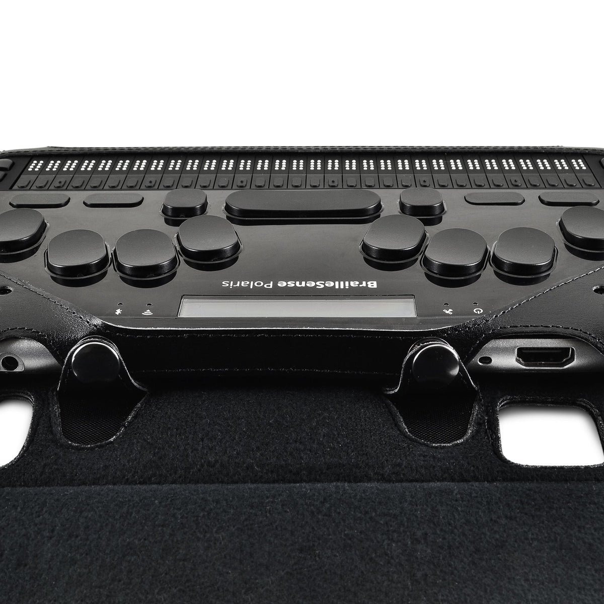 Close-up from above of BrailleSense Polaris braille keyboard and side connection port, framed by protective leather corners.