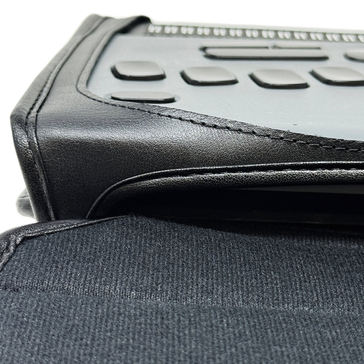 Close-up of the BrailleNote Evolve case's stitched leather border and fabric flap, with the device's buttons visible above it.