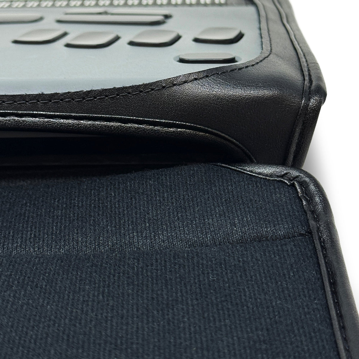 Close-up of the BrailleNote Evolve case's padded leather corner and open fabric flap, with braille device controls visible.