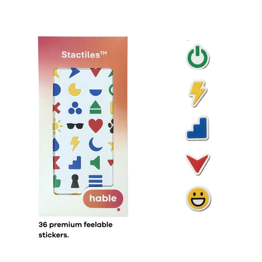 A composite image featuring fingers touching various colorful 3D tactile stickers on a white sheet. The icons include a red heart, a yellow star, and a blue crescent moon. In the bottom-left corner, a yellow lightning bolt sticker is shown placed on a person’s fingertip to demonstrate its size. The Hable Stactiles product packaging and a full sheet of icons are displayed on the right.
